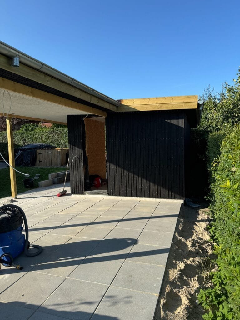 Nybygget sort skur med flisebelagt terrasse