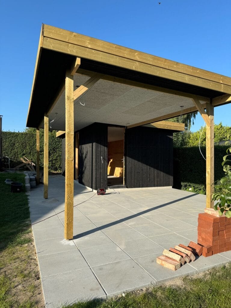 Nyopført carport med træstolper og flisebelægning