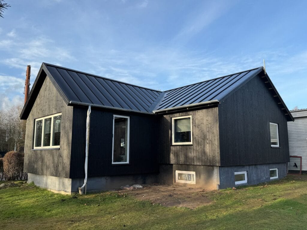 Sort træhus med metaltag i solskin