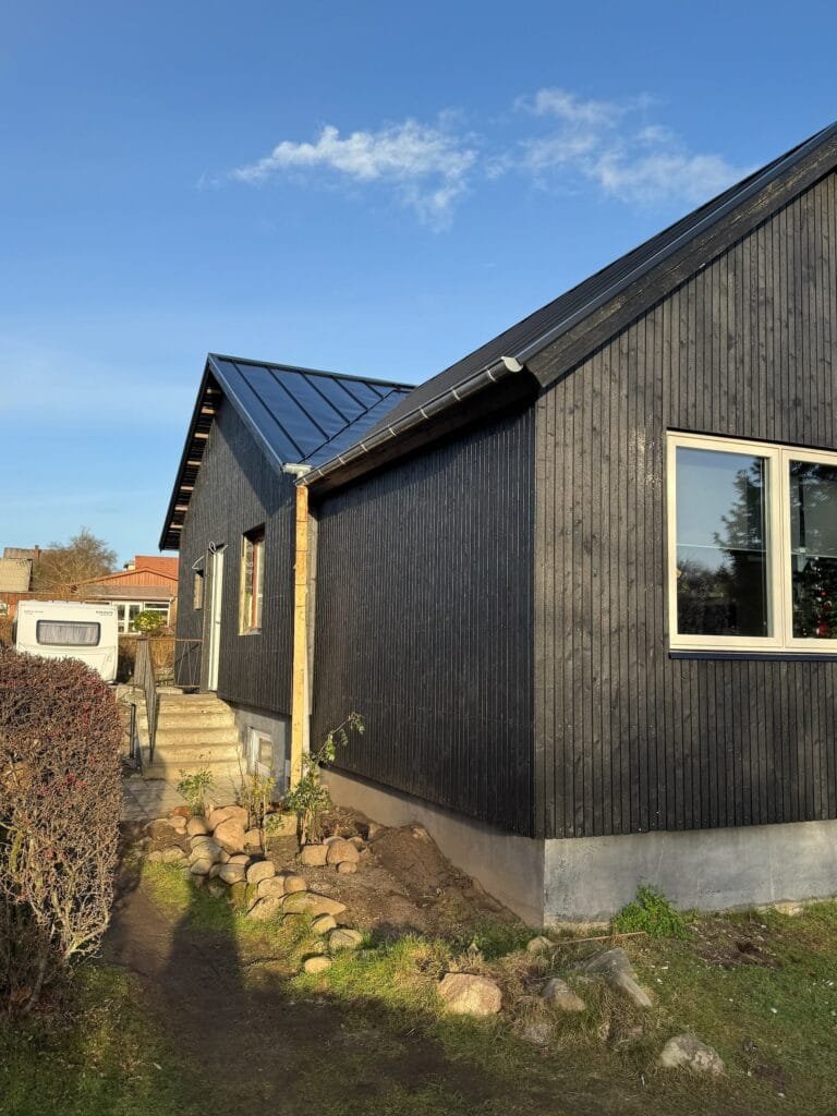 Moderne sort træhus med skråt tag i solskin