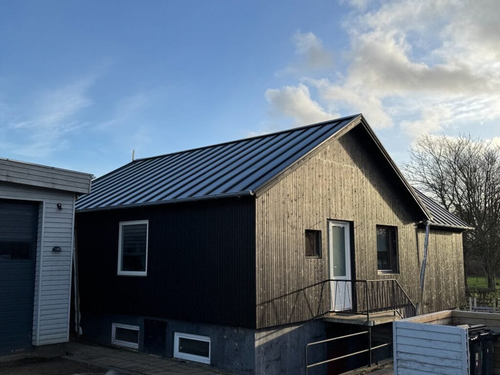 Træhus med sort tag og blå himmel