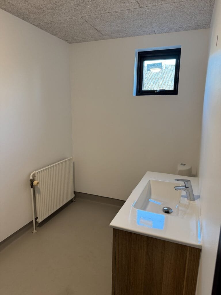Lyst badeværelse med håndvask og lille vindue